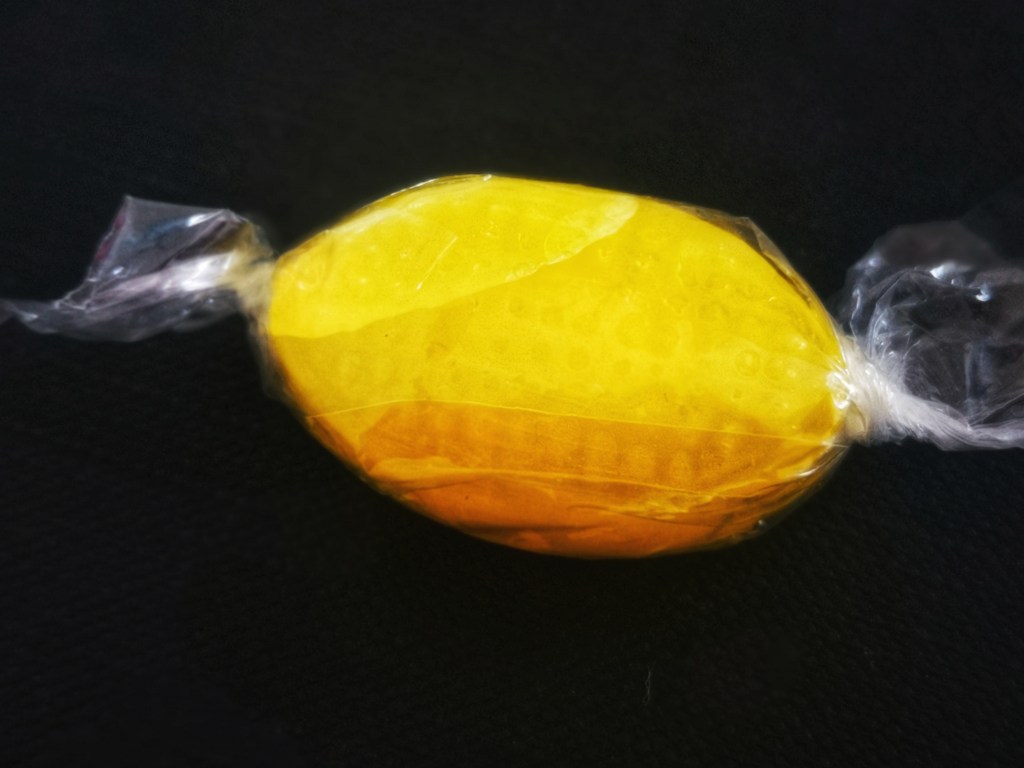 Hellow hard candy wrapped in transparend foil on black background 