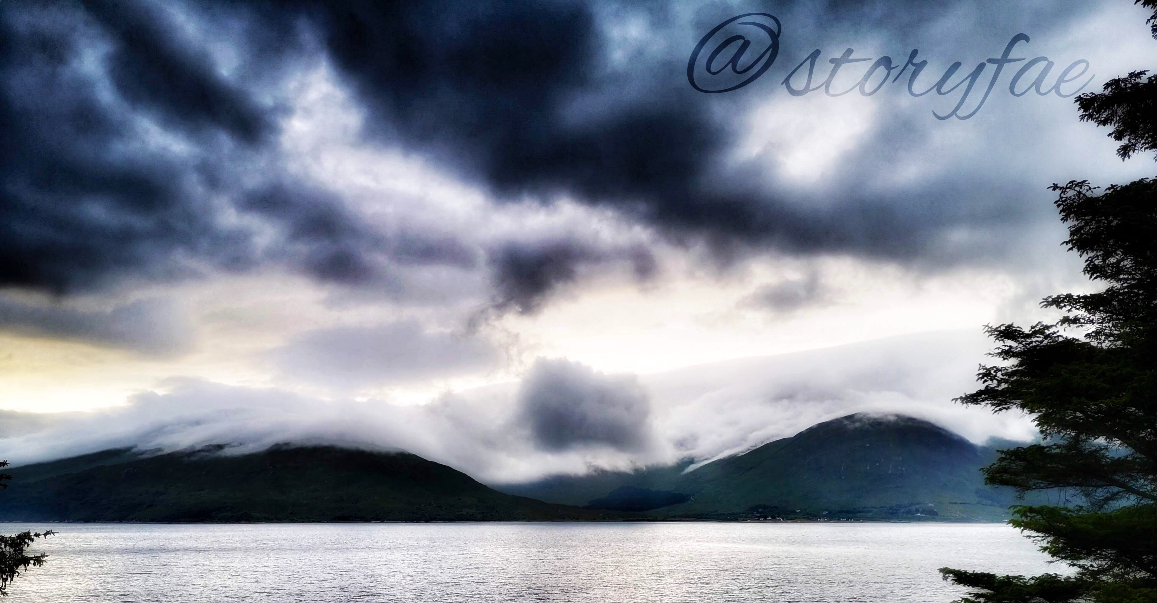 low clouds rolling on mountains in the Scottish Highlands, photo taken from across the bay looking towards the mountains
Watermark @storyfae